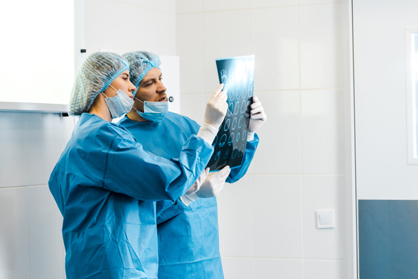 krásní a krásní lékaři v uniformách, kteří drží rentgen a mluví - Fotografie, Obrázek