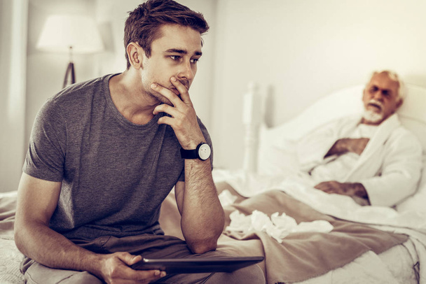 Worried man thinking of the illness of his aging father - Photo, Image