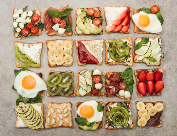Vue de dessus des toasts aux œufs frits, légumes coupés et fruits sur surface texturée
 - Photo, image