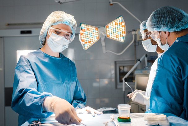 equipo de mantenimiento de enfermería y médicos en uniformes y gorras médicas en quirófano
 - Foto, Imagen