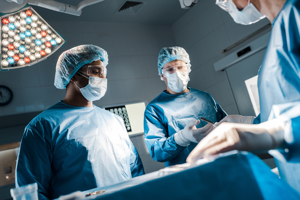 γιατρούς και νοσοκόμα σε στολές και ιατρικές μάσκες στο χειρουργείο  - Φωτογραφία, εικόνα