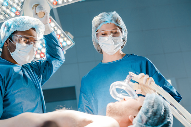 селективний фокус пацієнта, лікаря та медсестри в уніформі та медичній кришці, що тримає маску
 - Фото, зображення