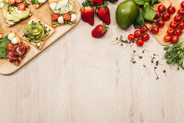 vue du dessus des toasts aux légumes et au prosciutto sur table en bois avec ingrédients
  - Photo, image