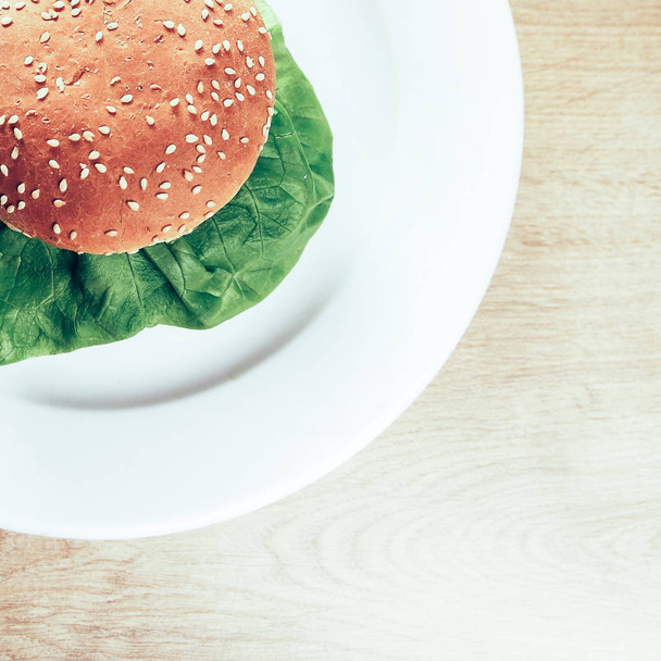 hamburger on a white plate on wooden background - Foto, afbeelding