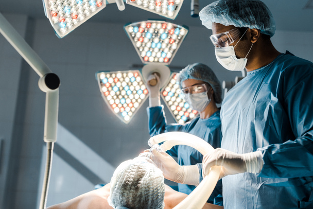 enfoque selectivo del cirujano en uniforme y gorra médica que pone la máscara en el paciente
  - Foto, Imagen