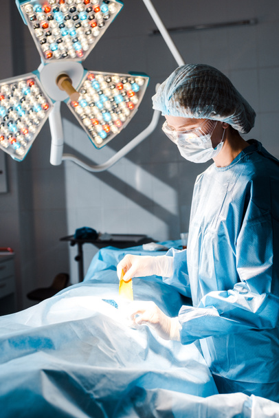 Enfermera en uniforme y tira de sujeción de gorra médica en quirófano
  - Foto, imagen
