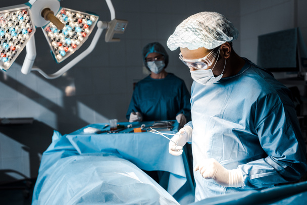 επιλεκτική εστίαση του χειρουργού σε ομοιόμορφο και ιατρικό καπάκι που κάνει τη λειτουργία  - Φωτογραφία, εικόνα