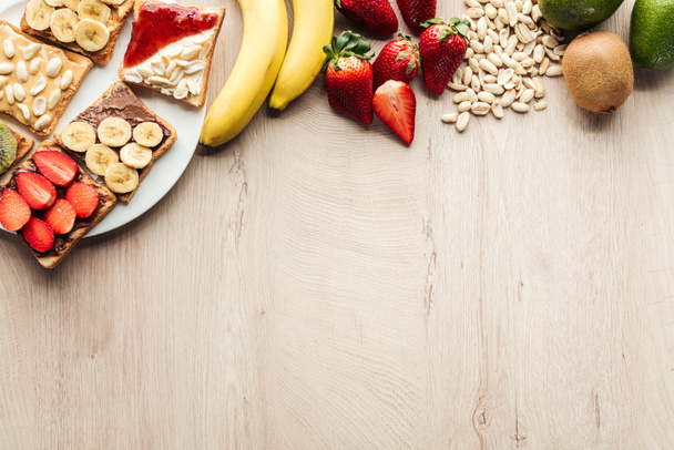 top view of bananas, strawberries, peanuts and toasts on wooden table with copy space - 写真・画像