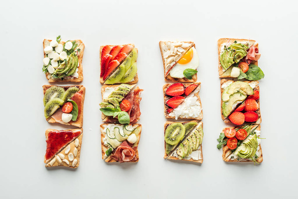 top view of tasty toasts with fruits, vegetables and basil isolated on white - Fotoğraf, Görsel