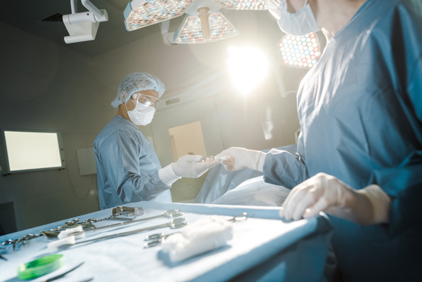 Selektywny fokus pielęgniarki dając sprzęt medyczny do chirurga w sali operacyjnej  - Zdjęcie, obraz