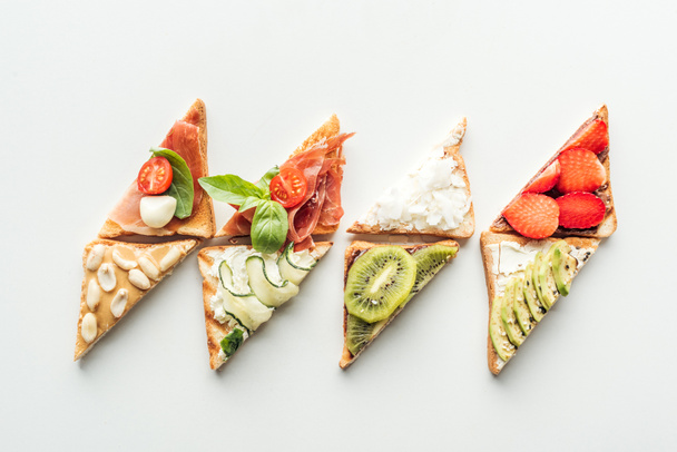 top view of toasts with strawberries, avocado, kiwi and prosciutto isolated on white - Foto, Imagem