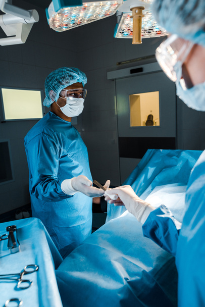 enfoque selectivo de la enfermera que proporciona equipo médico al cirujano en quirófano
  - Foto, Imagen
