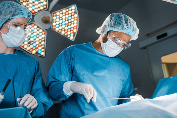 enfermera y cirujano en uniformes y máscaras médicas haciendo la operación
  - Foto, Imagen