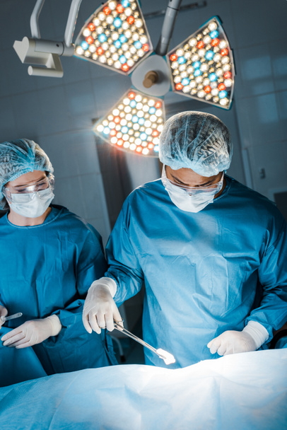enfermera y cirujano en uniformes y máscaras médicas haciendo la operación
  - Foto, imagen