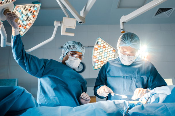 enfermera y cirujano en uniformes y máscaras médicas hablando en quirófano
  - Foto, imagen