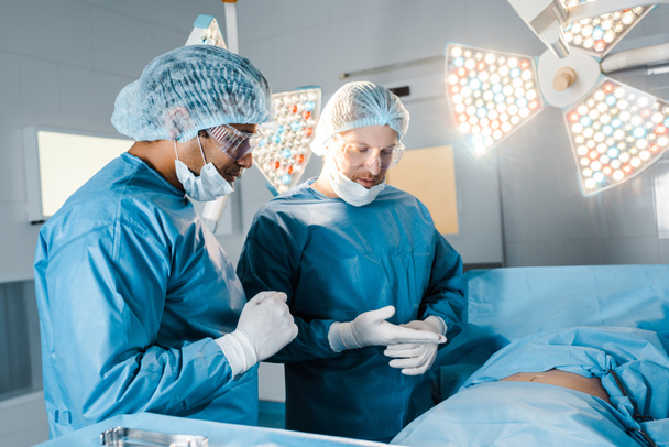 pielęgniarka i chirurg w mundury i maski medyczne rozmawiając w sali operacyjnej  - Zdjęcie, obraz
