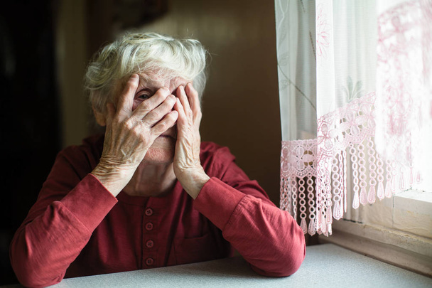 Ηλικιωμένη γυναίκα, που καλύπτουν το πρόσωπο με τα χέρια της και να κρυφοκοιτάζουν μέσα από τα δάχτυλά. - Φωτογραφία, εικόνα