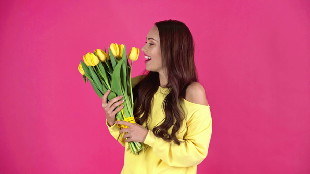 studio shoot of happy young woman holding bouquet of yellow tulips on crimson background - Footage, Video