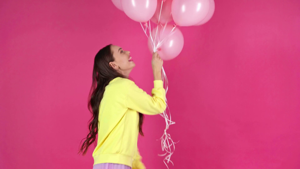 Stüdyo ateş pembe hava balonları tutarak ve koyu kırmızı zemin üzerine dans mutlu genç kadın - Video, Çekim