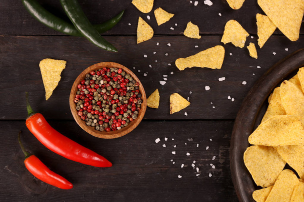 Mexické nachos v dřevěné nádobě tortilla Chips s chilli papričkami a solí, horním výhledem a černým pozadím - Fotografie, Obrázek