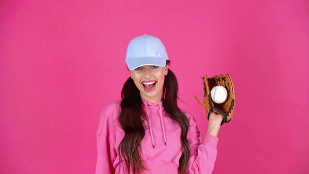 studio shoot of attractive happy young woman in cap catching ball with baseball glove - Footage, Video