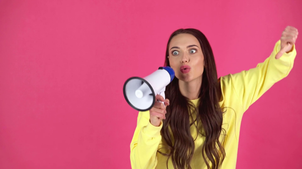 studio shoot of beautiful angry young woman speaking in loudspeaker,pointing with finger, showing thumb down  - Filmagem, Vídeo