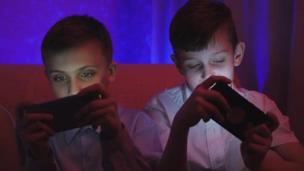 Two cute boys playing video game with smart phone in the room - Footage, Video