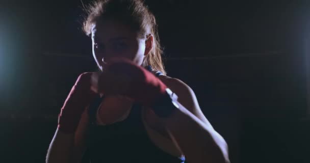 Дивлячись в камеру, красива жінка-боксер вражає на темному тлі з підсвічуванням. Стейдікам постріл
 - Кадри, відео