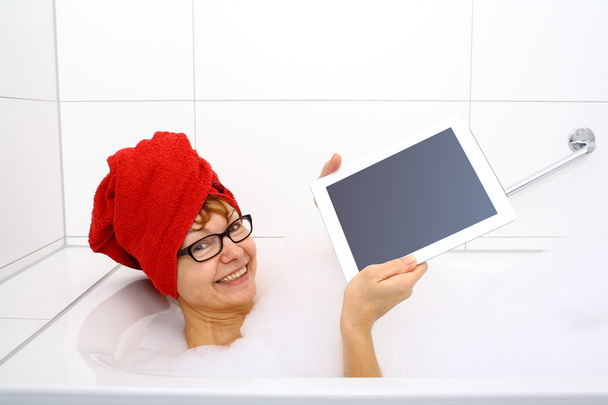 Femme heureuse dans la baignoire avec des ordinateurs tablettes
 - Photo, image