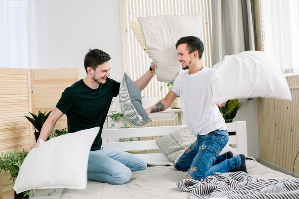 Portrait de jeune couple gay ayant bataille d'oreillers dans la chambre
 - Photo, image