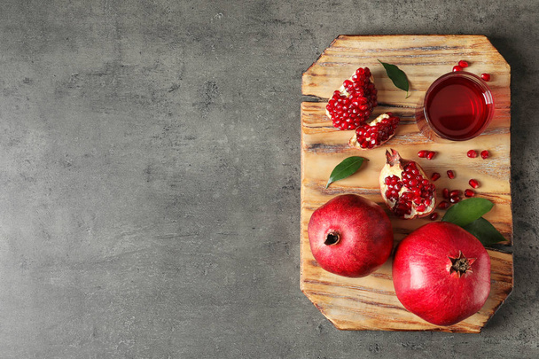 Board with glass of pomegranate juice and fresh fruits on grey background, top view. Space for text - Fotó, kép