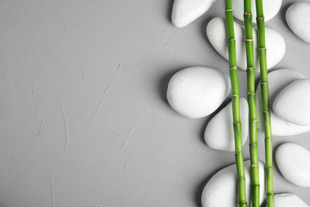 Zenové kameny a bambus na šedém pozadí, pohled shora s prostorem pro text - Fotografie, Obrázek