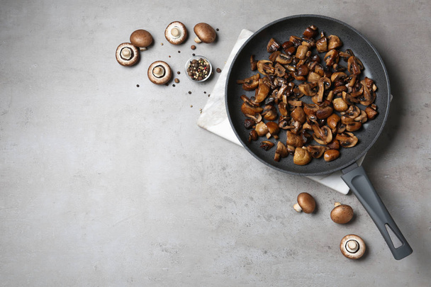 Frying pan of mushrooms on grey background, flat lay with space for text - Fotó, kép