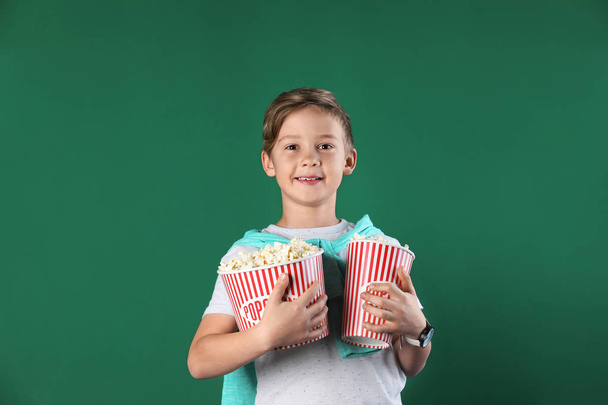 Cute boy with popcorn buckets on color background - Foto, afbeelding