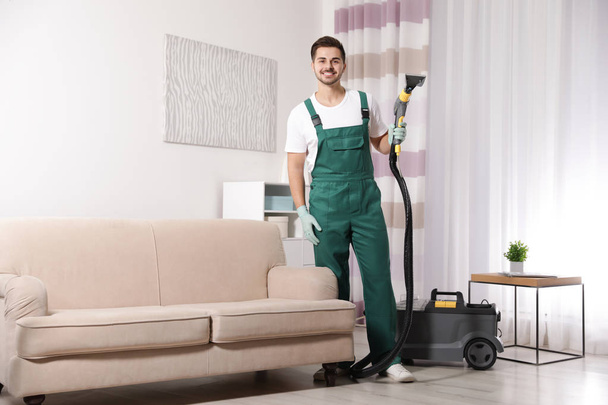 Professional janitor cleaning sofa in living room - Valokuva, kuva