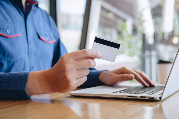 Επιχειρηματίας κρατώντας πιστωτική κάρτα και πληκτρολογώντας στο φορητό υπολογιστή για online  - Φωτογραφία, εικόνα