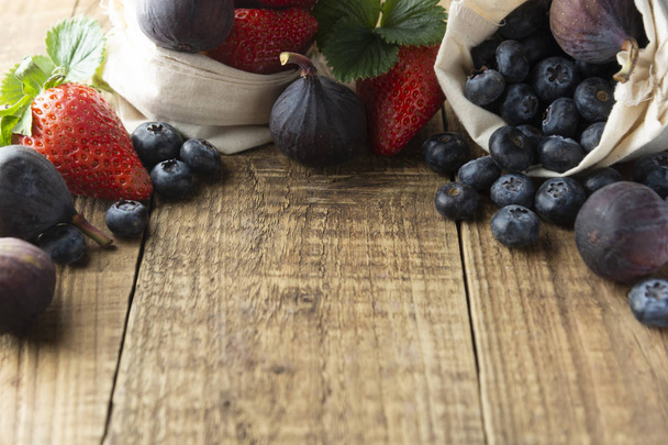 Frame met vruchten met aardbeien, bosbessen, vijgen op rustieke gestructureerde achtergrond. De achtergrond van de fruit voor het ontbijt met kopie ruimte. Plat lag, top uitzicht. - Foto, afbeelding