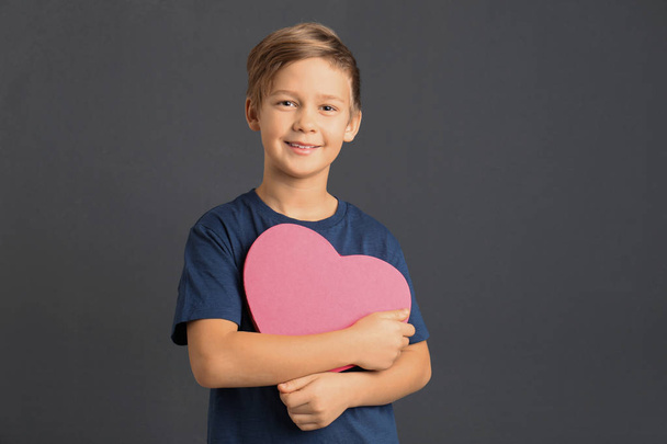Egy aranyos fiú, szív alakú doboz szürke háttérrel - Fotó, kép