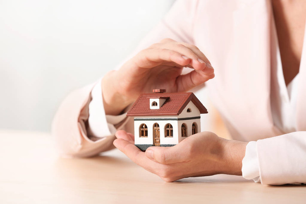 Female agent covering house model at table, closeup. Home insurance - Photo, Image