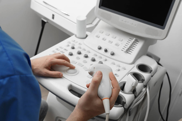 Sonographer operating modern ultrasound machine in clinic, closeup - 写真・画像