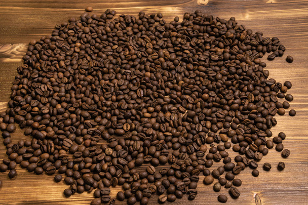 Roasted coffee beans in bulk on a wooden background - Фото, изображение