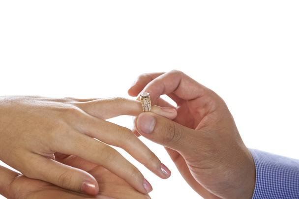 junge erwachsene männliche Hand legt Verlobungsring auf weiblichen Finger - Foto, Bild
