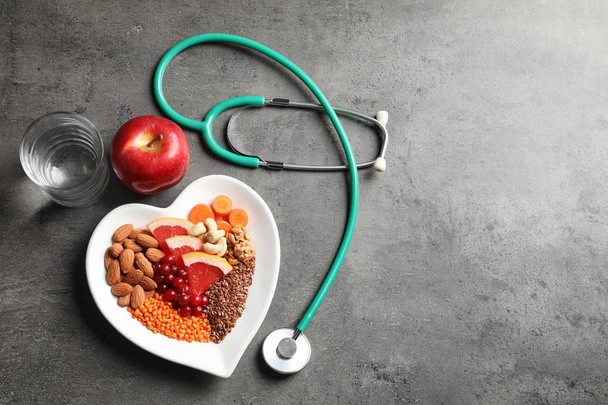 Flat lay composition with plate of heart-healthy diet products and space for text on grey background - Foto, immagini