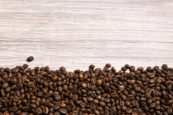Roasted coffee beans in bulk on a light wooden background. dark  - Zdjęcie, obraz