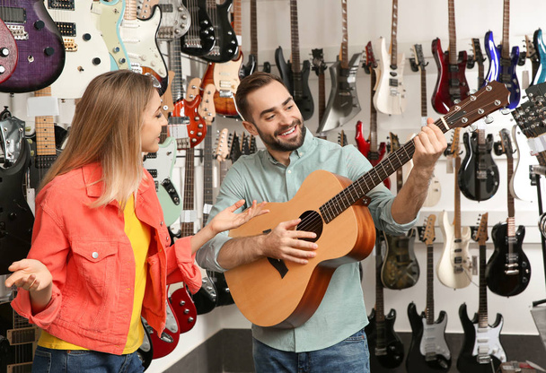 Young people choosing guitar in music store - Фото, изображение