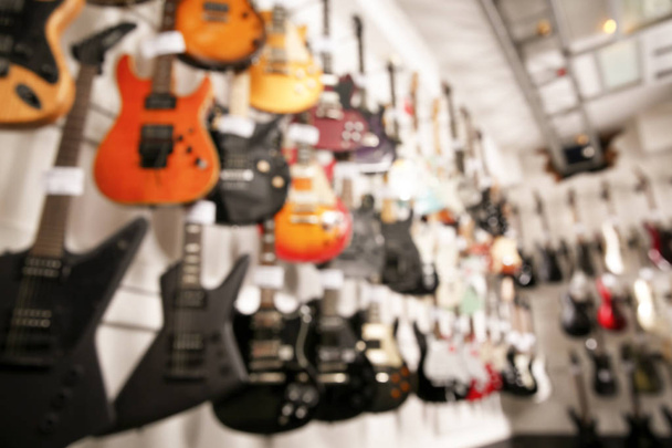 Rows of different guitars in music store, blurred view - Foto, Imagen