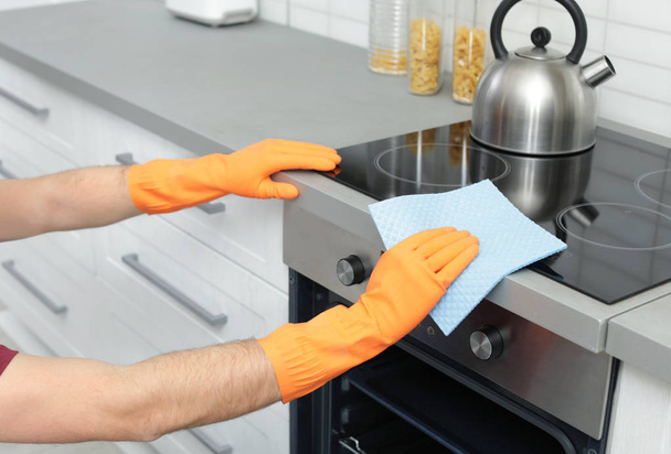 Young man cleaning oven with rag in kitchen, closeup - Foto, Bild