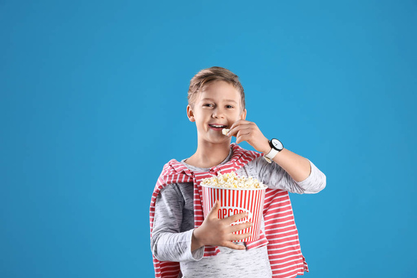 Cute boy with popcorn bucket on color background - Photo, Image