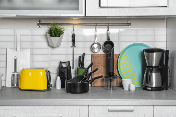 Kochgeschirr, sauberes Geschirr und Geräte auf dem Küchentisch - Foto, Bild