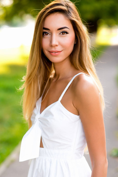 Beautiful and happy girl in white dress, long hair, close-up in the summer in the city outdoors. Emotions joy fun holiday, walk in the park lifestyle. - Photo, Image